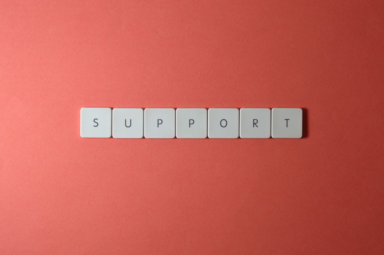 Close-up of the word 'support' spelled with keyboard keys on a red background.
